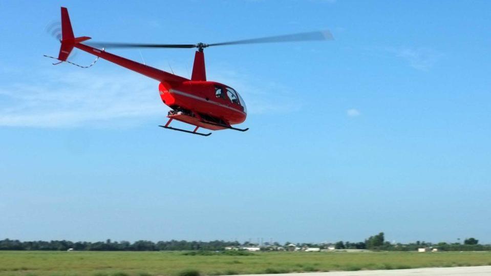 The Tier 1 Engineering electrified version of the Robinson R44 lifts off from a taxiway.