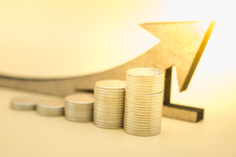 Money, business, saving and growth concept. Close up of stack of silver coins with wooden arrow symbol.