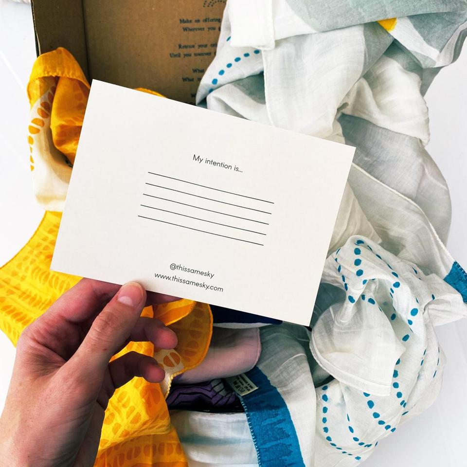 A note card saying ″My intention is″ against background of a white and blue scarf