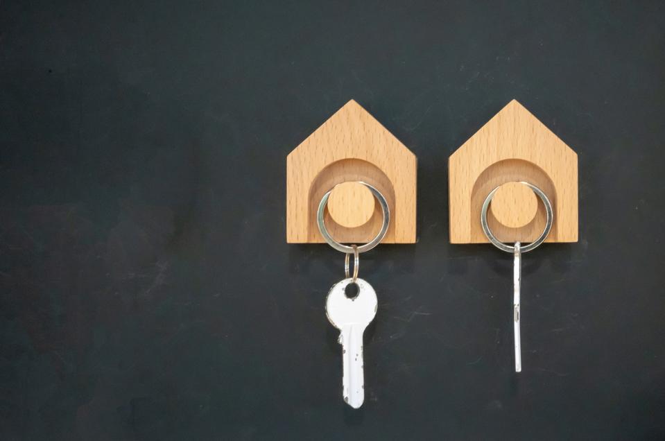 Wooden key hanger against black wall background.