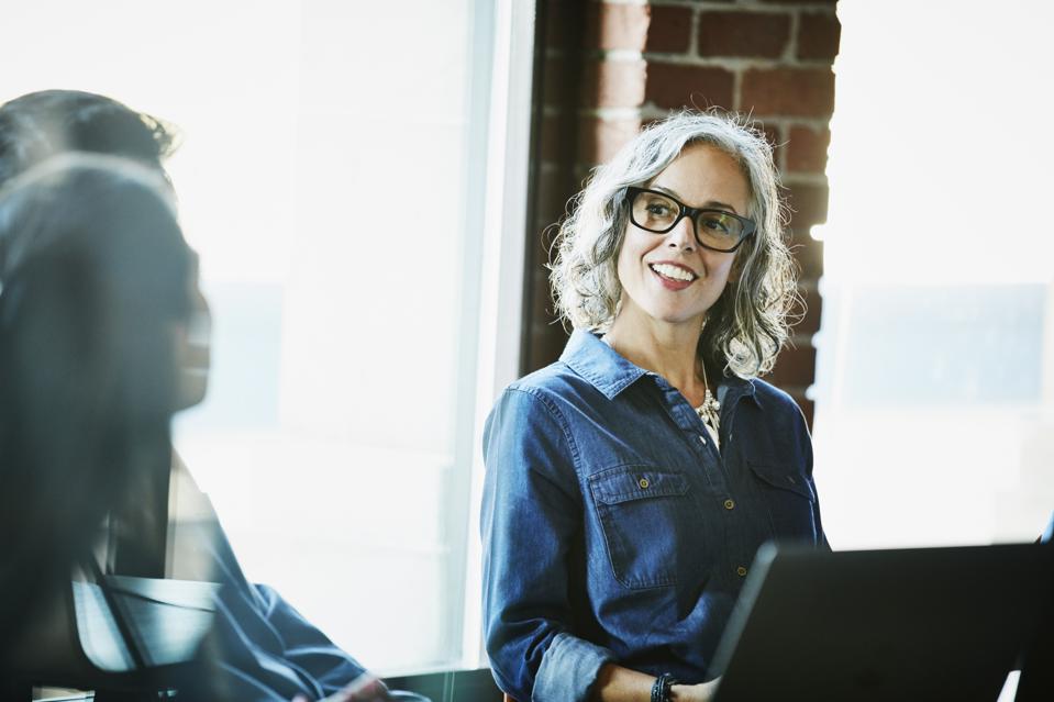 Smiling businesswoman leading meeting with clients in conference room