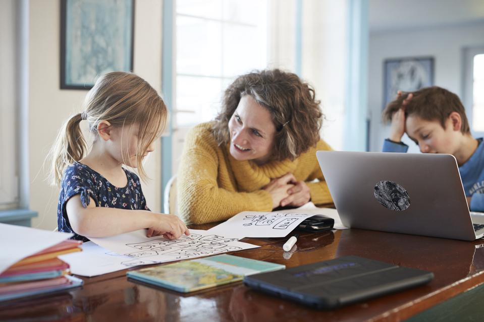 Mother homeschooling daughter and son at table