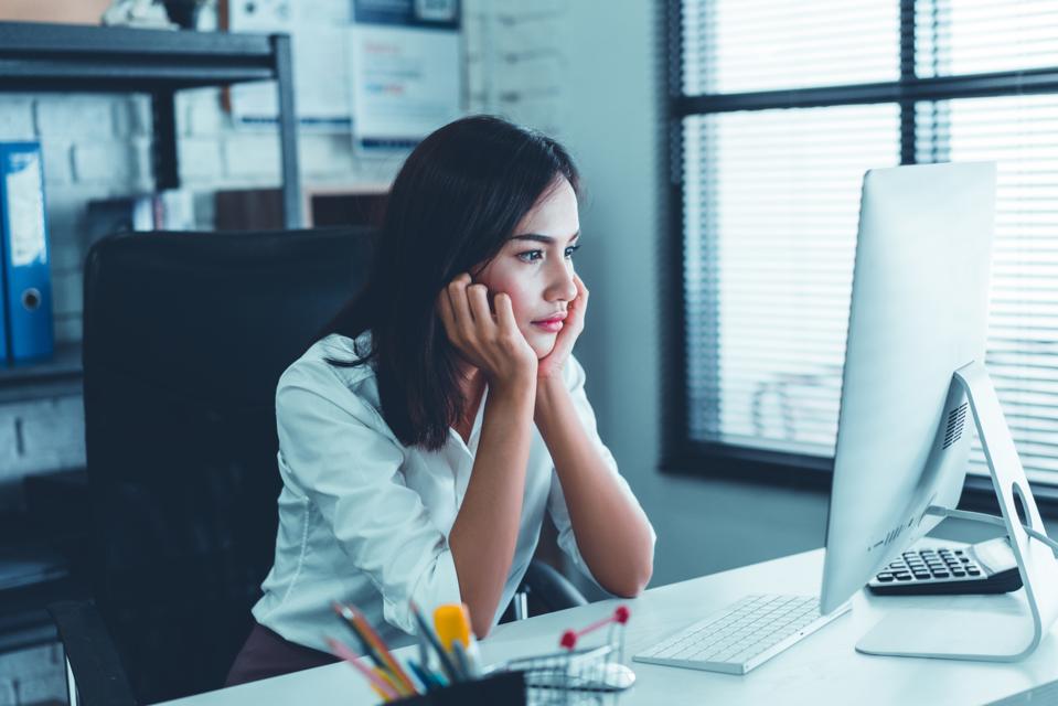 Unhappy female professional at work computer with head in hands