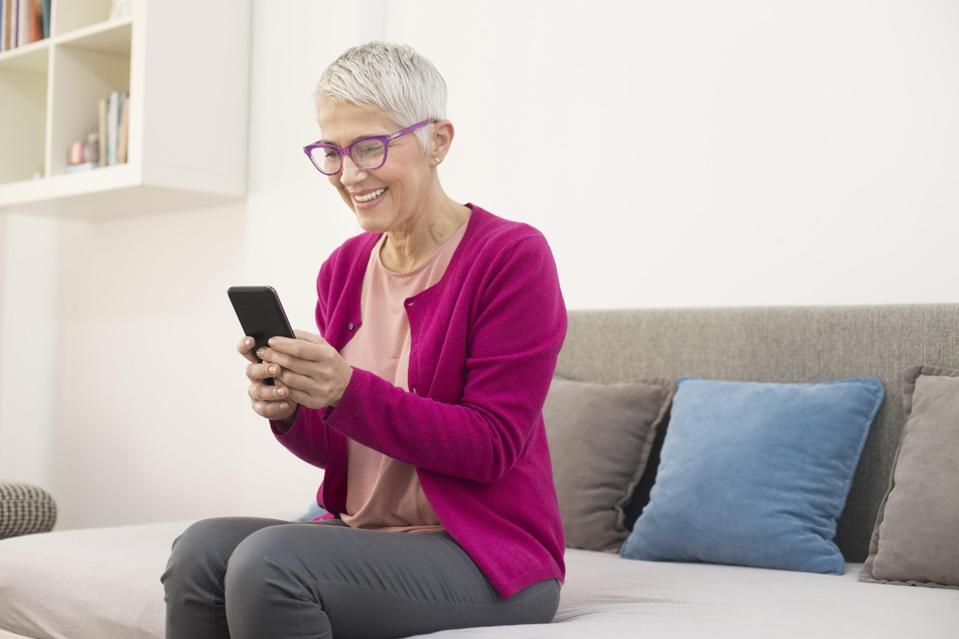 woman sitting on couch using phone