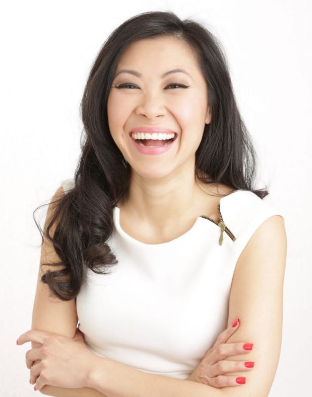 Melissa Leong smiling happily, long hair, arms crossed, wearing a sleeveless white top.