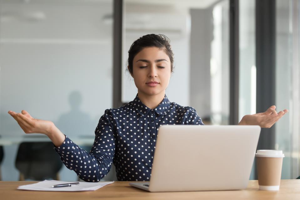 Calm serene office worker indian woman resting meditating at workplace