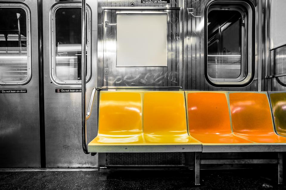 Picture of subway seats against a black and white subway car