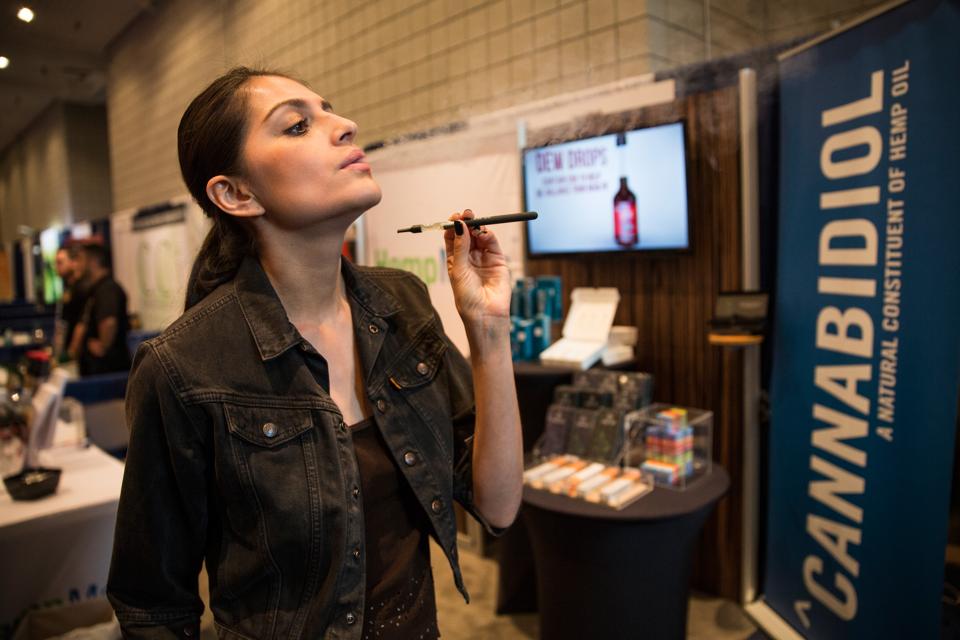 A woman poses while smoking a vape stick