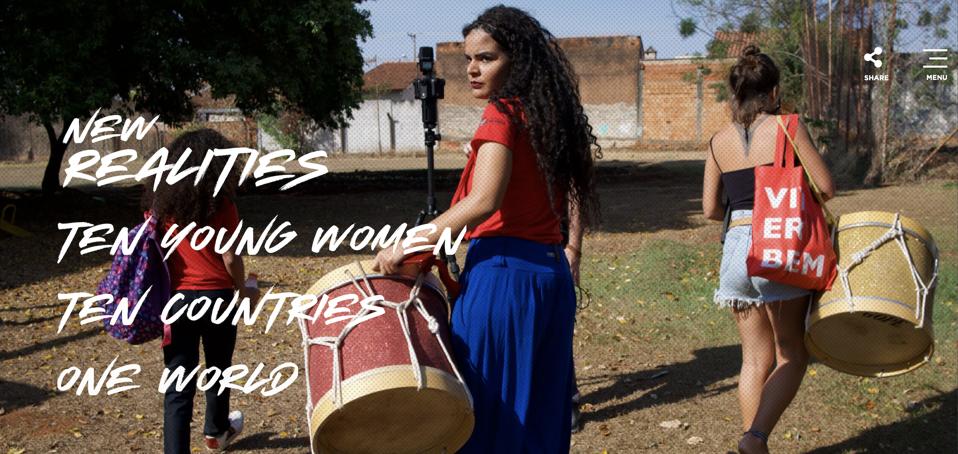 Three young women carrying drums and bags walking away from the camera in a rural area with one turning towards the camera. The words New Realities Ten youong women ten countries one world
