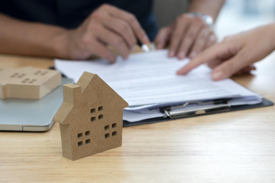 Customer signing a real estate contract in real estate agency.