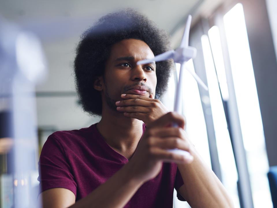 Focused African man looking at model of wind turbine