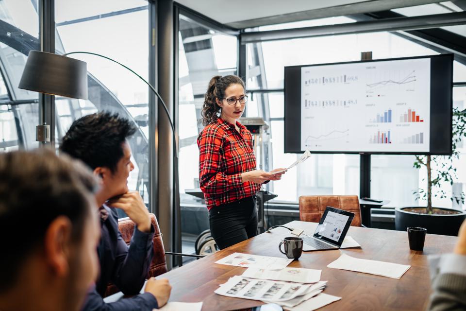 Woman Looking Over Charts And Data During Management Meeting