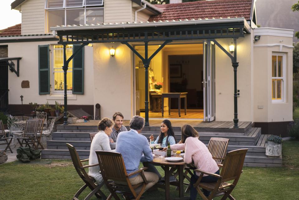 Family having food while sitting outside house