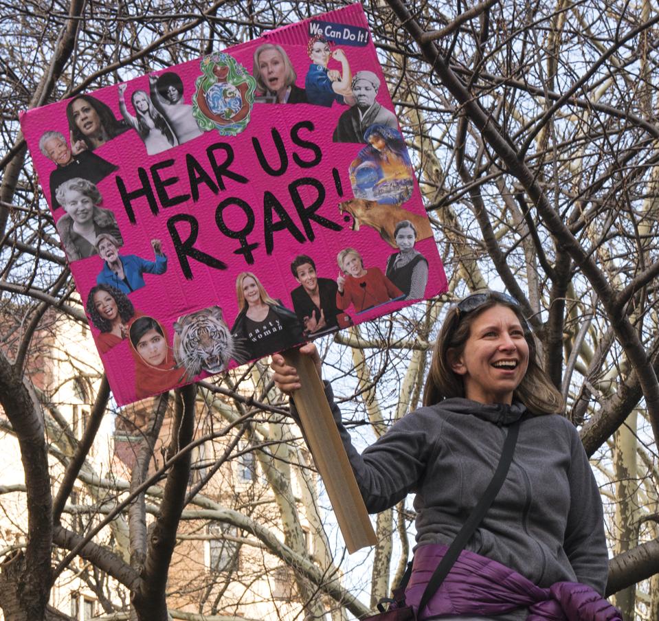 Woman holding ″hear us roar″ sign