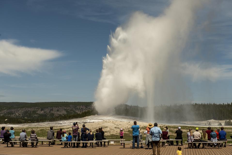Visitors watching an eruption of Old Faithful geyser in Yellowstone National Park, Wyoming.