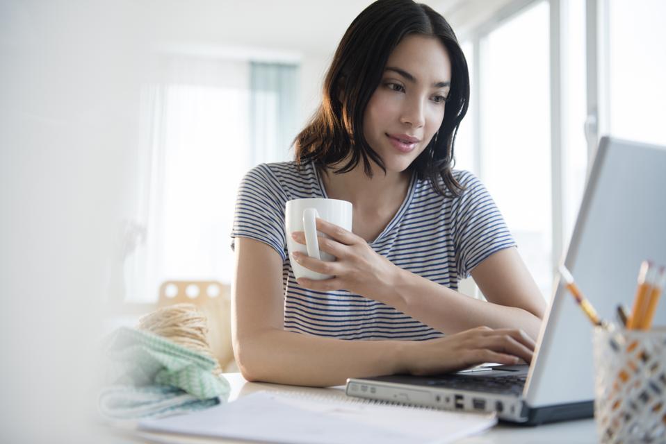 Hispanic woman using laptop at desk