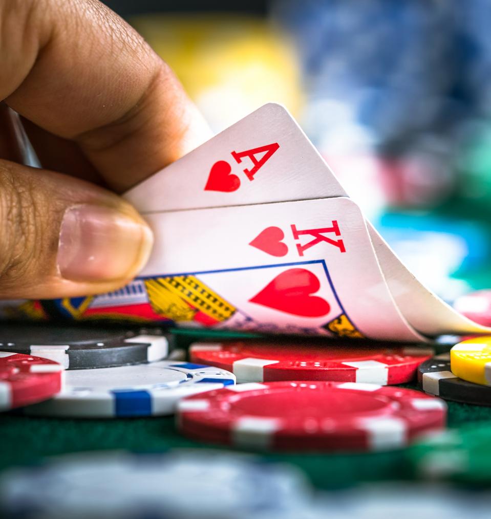 Gambling Hand Holding Poker Cards and Money Coins Chips