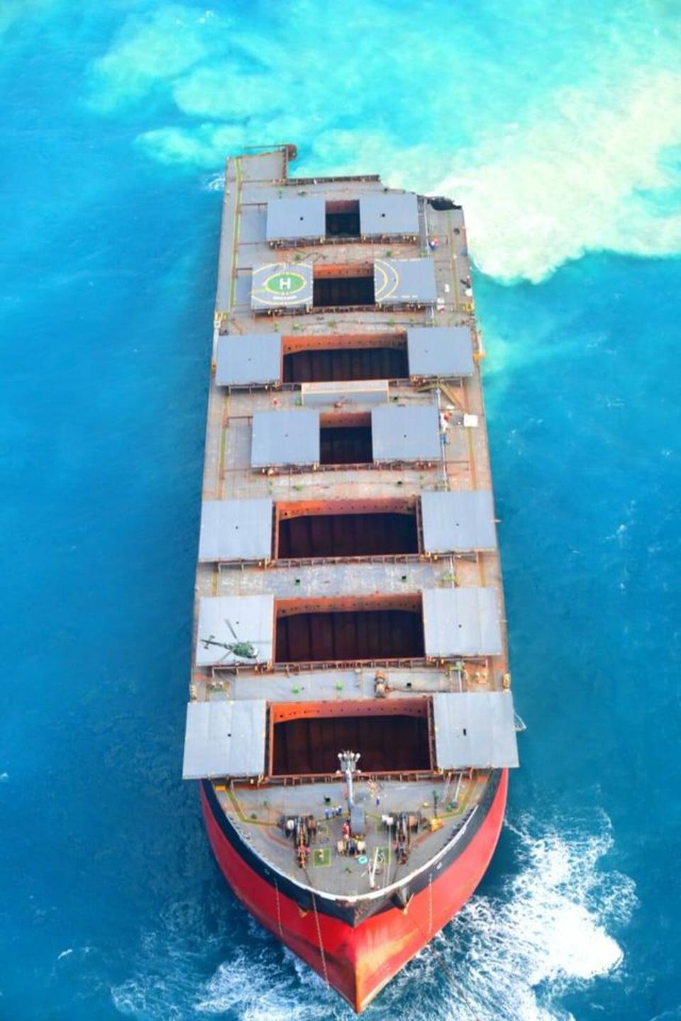 Scale of Mauritius' 'Chetak' helicopter (front starboard side by open hold door) can be seen in comparison to the massive hull of the Wakashio.  As part of the broken Wakashio is dragged off Mauritius' coral reefs on Aug 18.