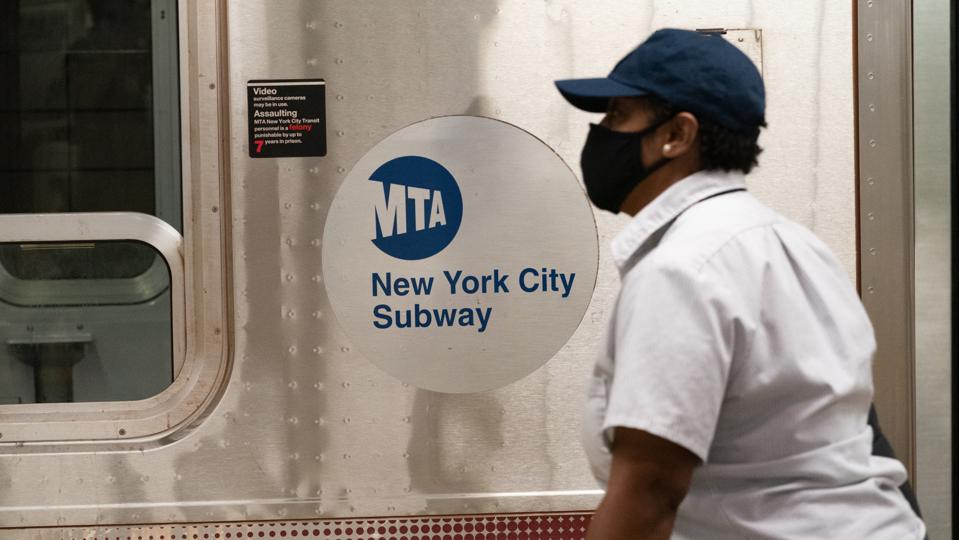 A woman wearing a face mask walks along the 34th Hudson...