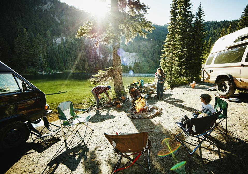 Father building fire while family sets up camp