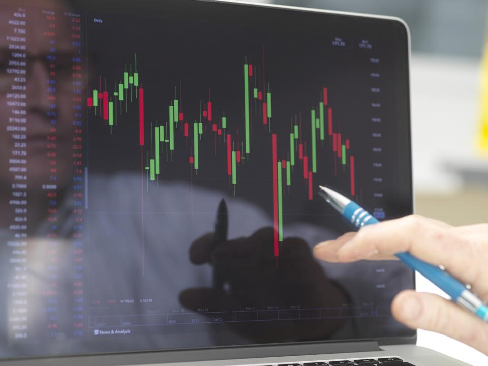 Reflection of a stock trader viewing the performance of a company share price on screen
