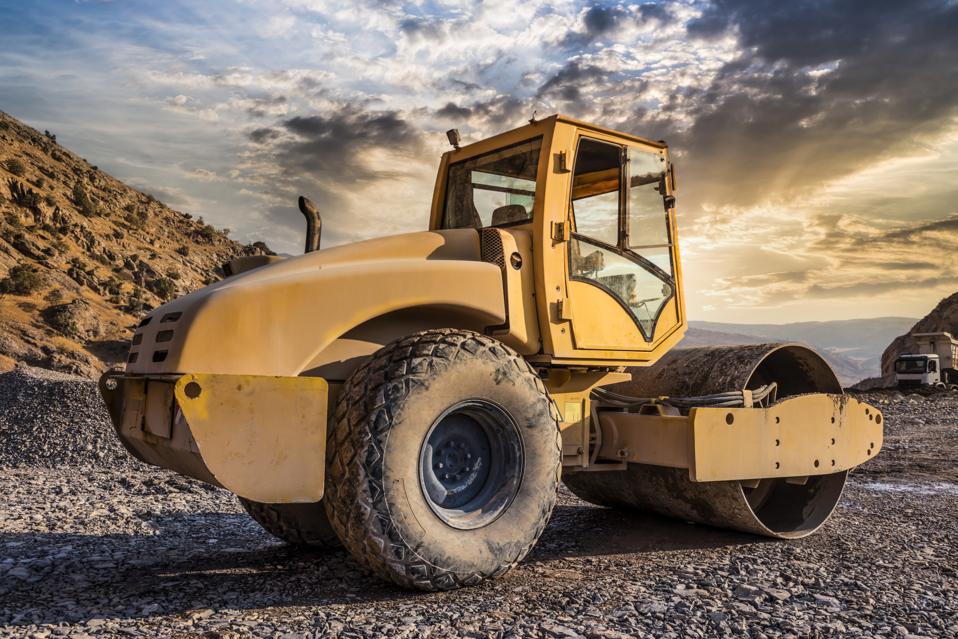 Roller compactor machine working at sunset
