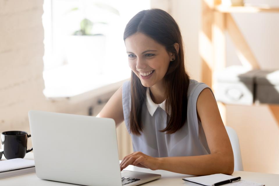 Happy young woman working at laptop at home