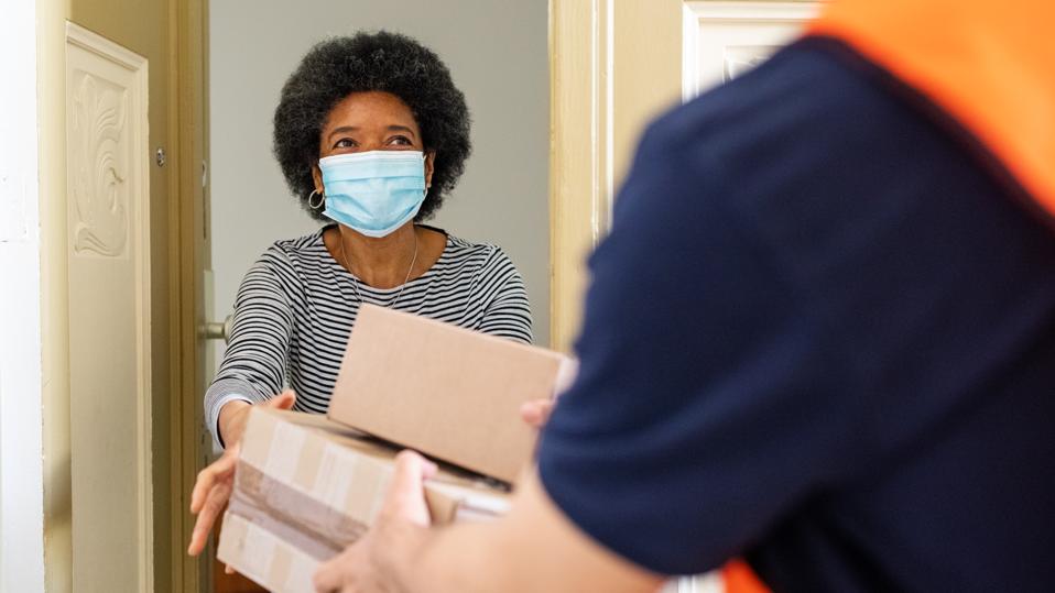 Woman getting package from delivery person during pandemic