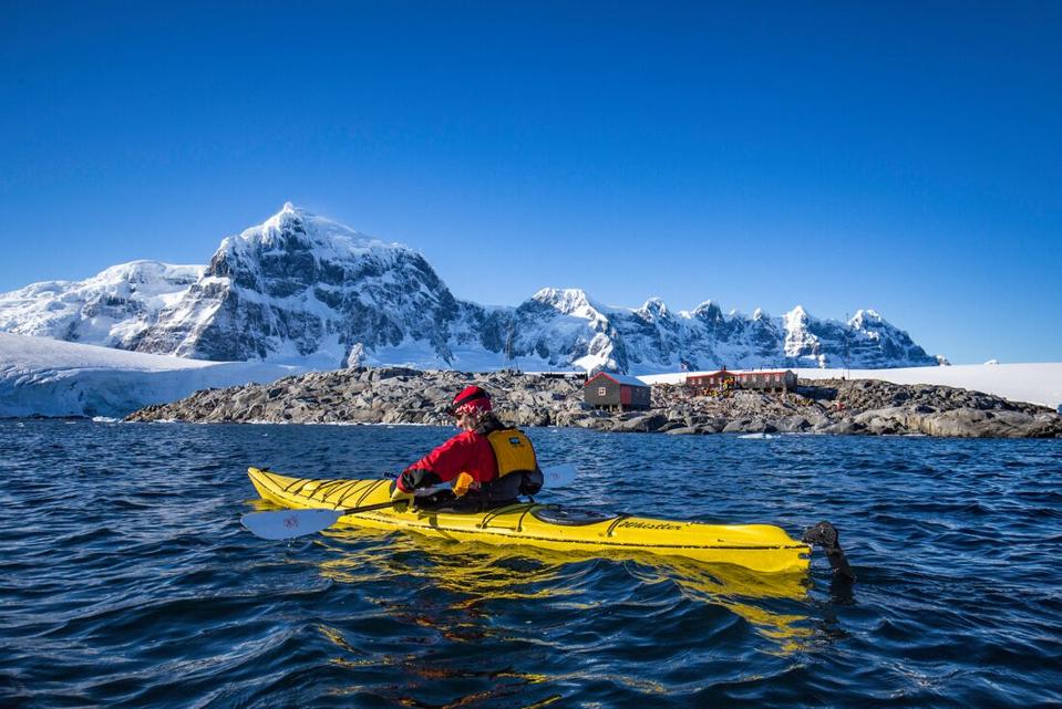 Kayaker in Antarctica surrounded by mountains covered in snow