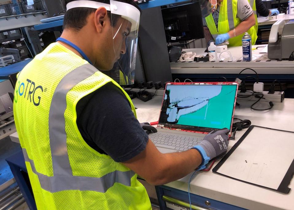 A computer technician repairs a cracked laptop screen at goTRG's facility in Arkansas.