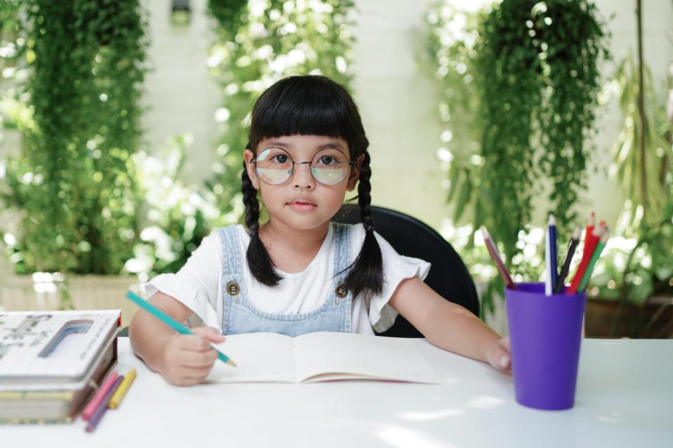 Asian student girl drawing and writing on the book for homework at home