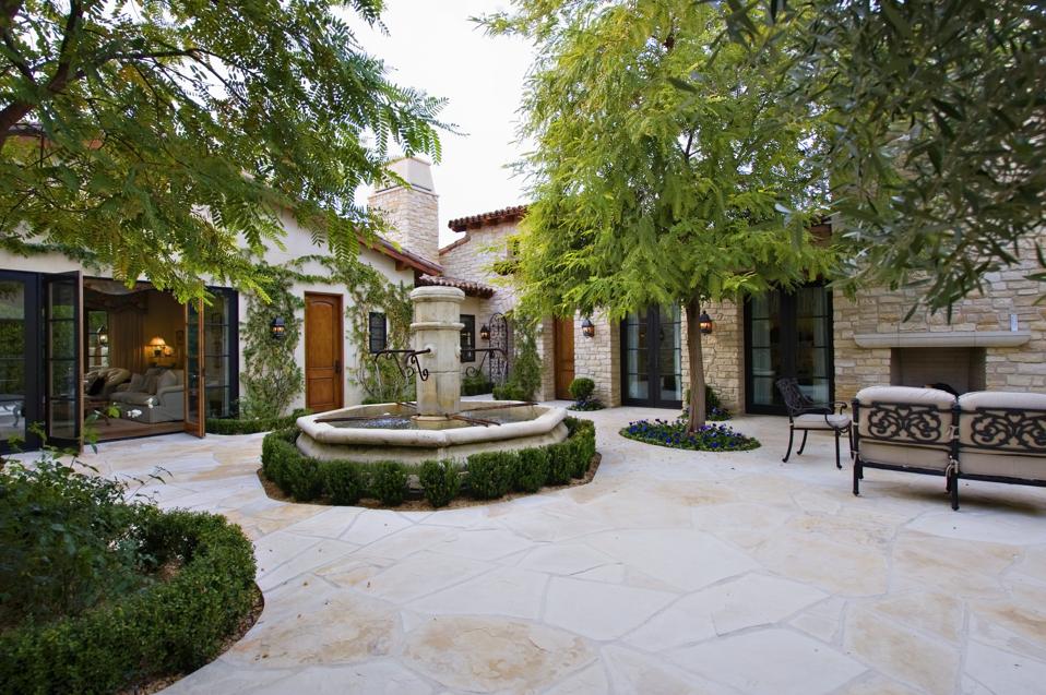 House exterior with a fountain, trees and patio furniture