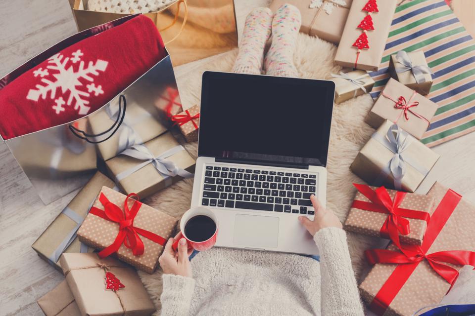Woman makes christmas shopping online with laptop, above view