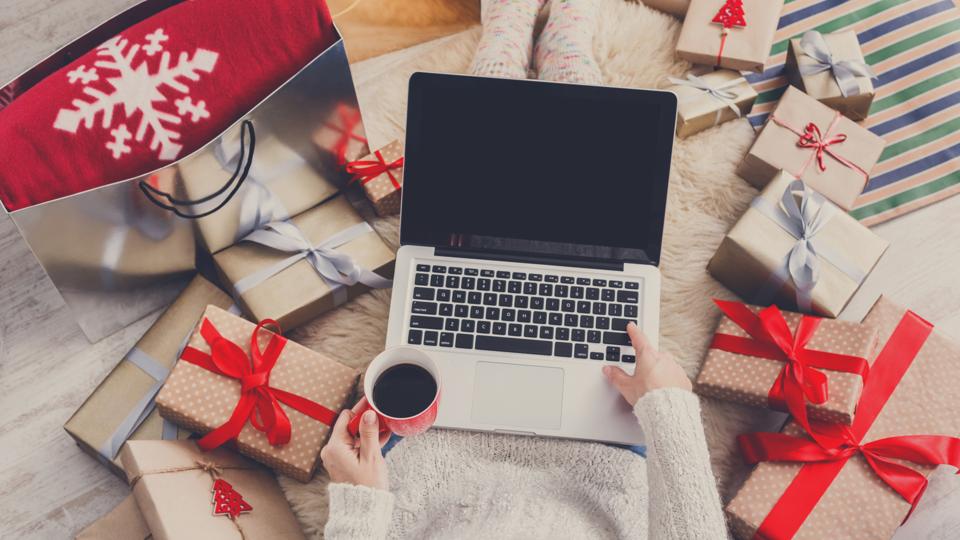 Woman makes christmas shopping online with laptop, above view