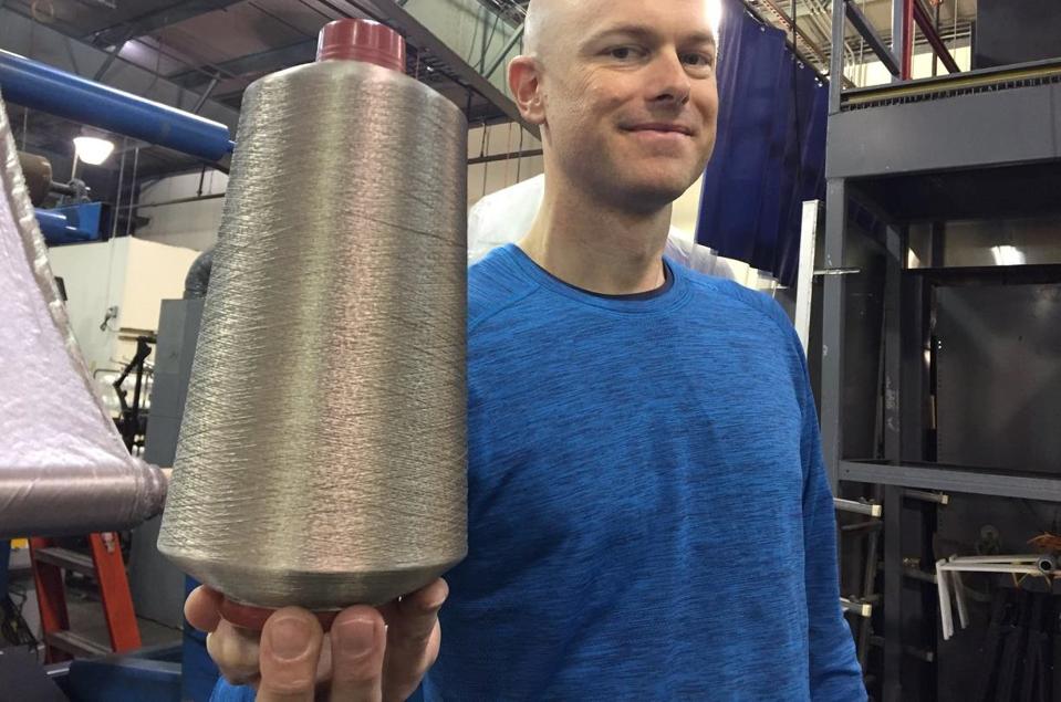Noble Biomaterials cofounder Joel Furey holding a cone of silver yarn.