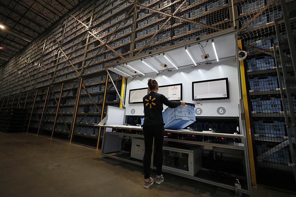 Walmart employee loads up Alphabot with an empty cart to be filled with an online order.