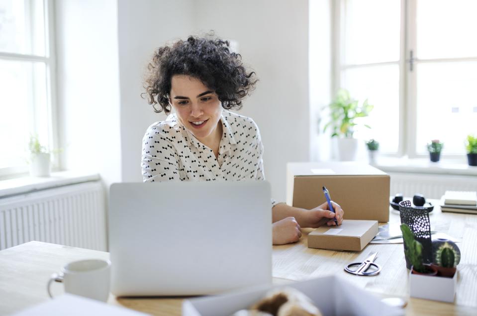 Smiling young woman preparing a package at desk