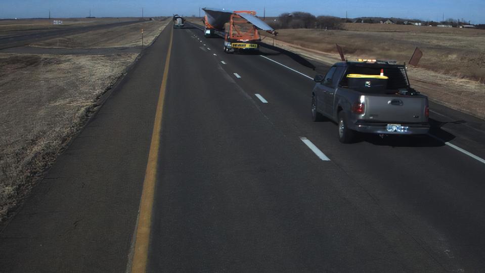 Truck on highway carrying wind turbine blade.