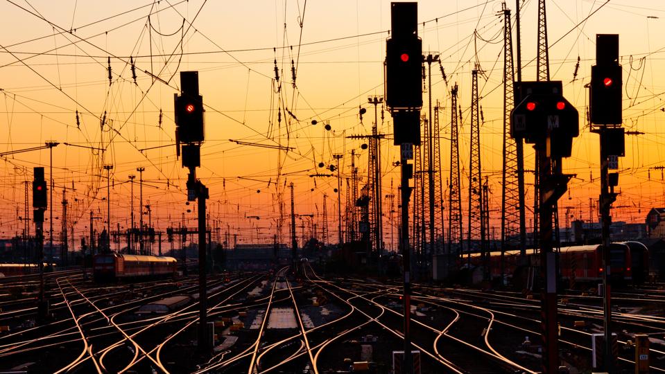 Intertwined railroad tracks with traffic lights at sunset