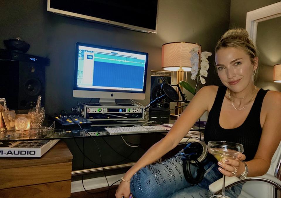 Jackie Schimmel holds a martini and sits in her podcast studio