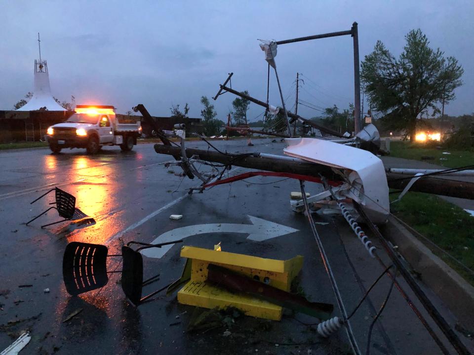 Plastic chairs lie in the road and metal from a damaged gas station roof is twisted around a downed power line in Jefferson City, Missouri on May 23, 2019.