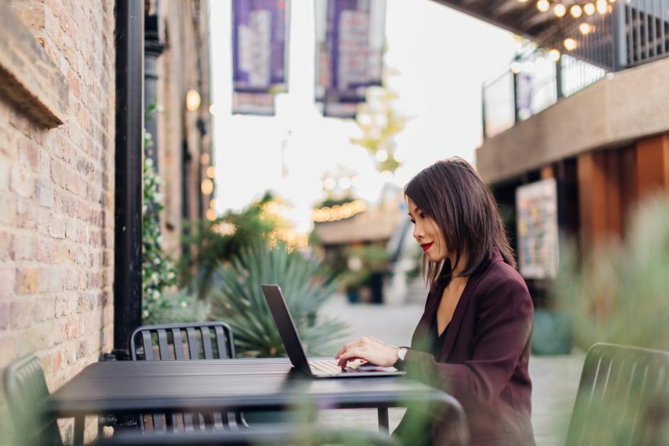 Young successful female freelancer working at an industrial style outdoor cafe