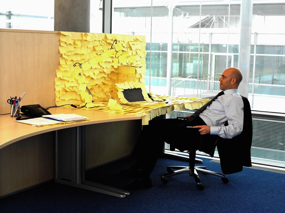 Man sitting at desk covered in yellow memo notes