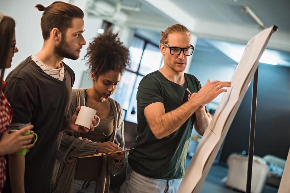 Co-workers having a discussion about something on an easel