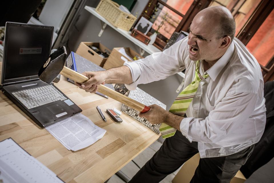 Businessman hitting hammer on laptop