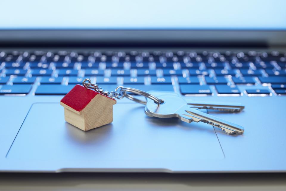 Still life of key ring with a small house and keys on laptop computer