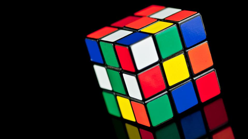 A classic Rubik's Cube puzzle on a reflecting background.