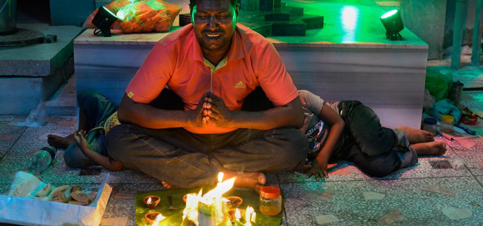 A devotee offering prayers next to lit candles during the...