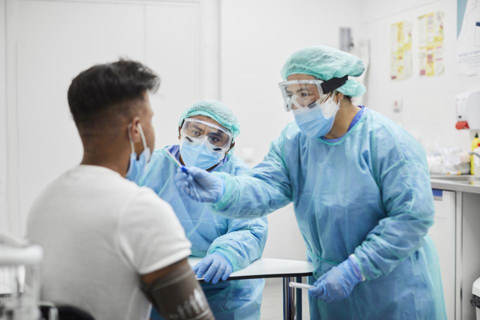 Female Doctor wearing protective equipment Taking Coronavirus Sample From Man