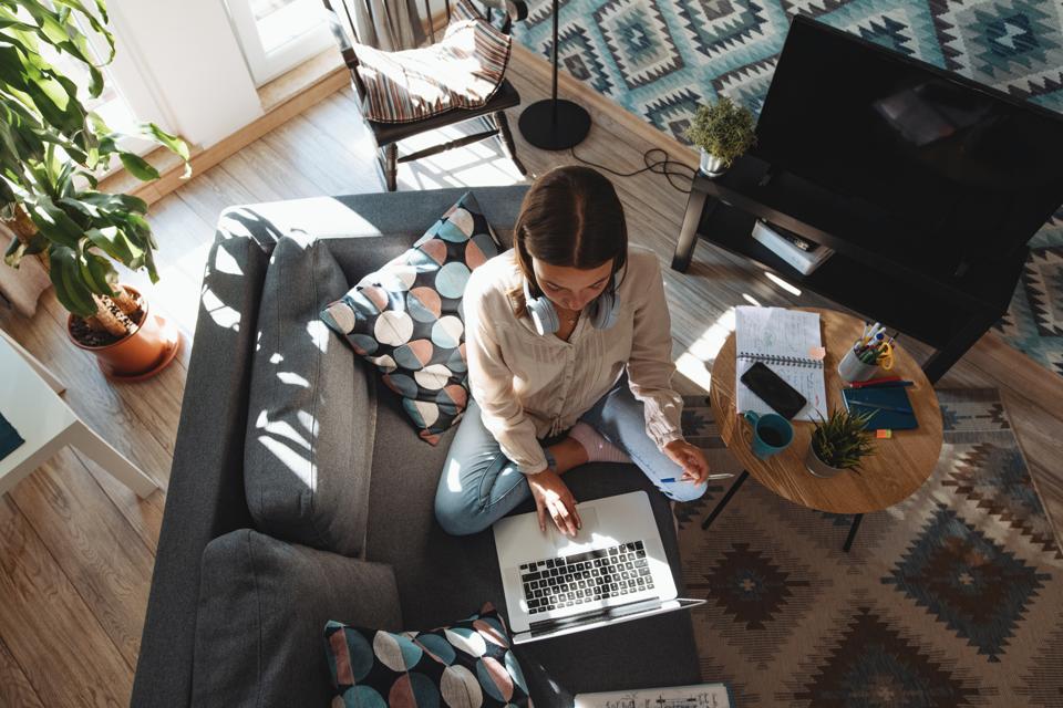 Woman working from home surrounded by throw pillows that probably cost way too much.